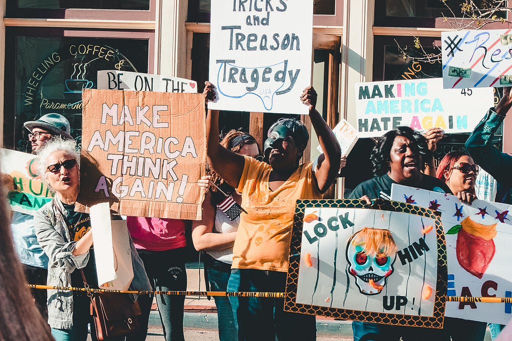 A group of protestors holding signs such as “Make America Think Again.”