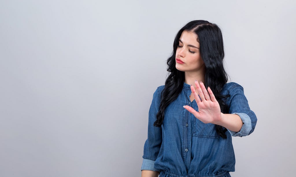 Woman holding up hand representing rejection.
