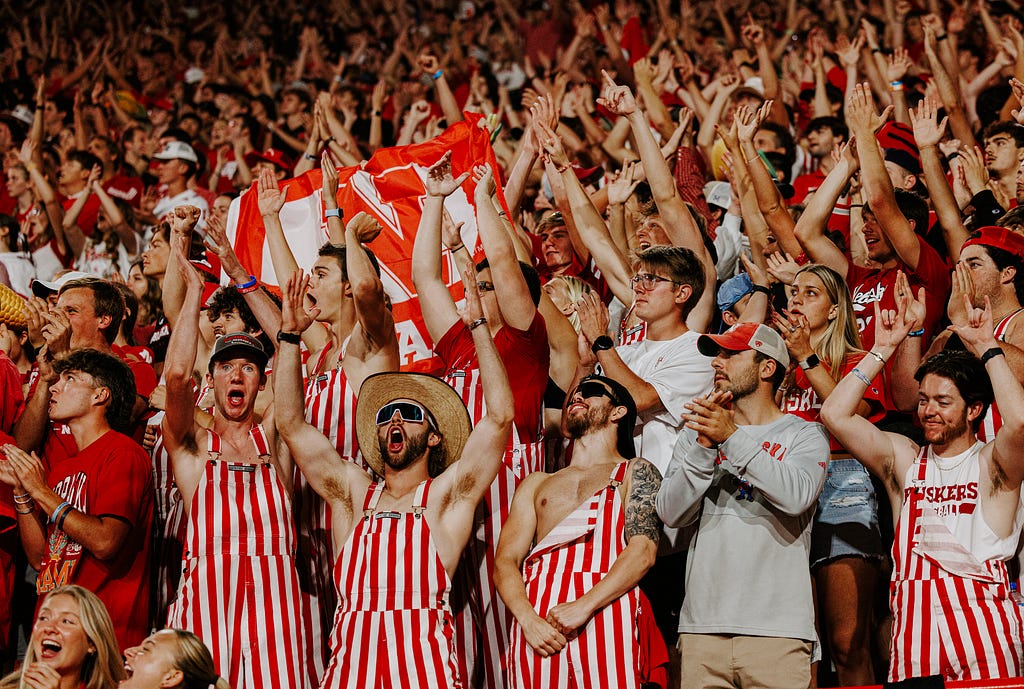 Fans in striped overalls cheer on the Husker football team