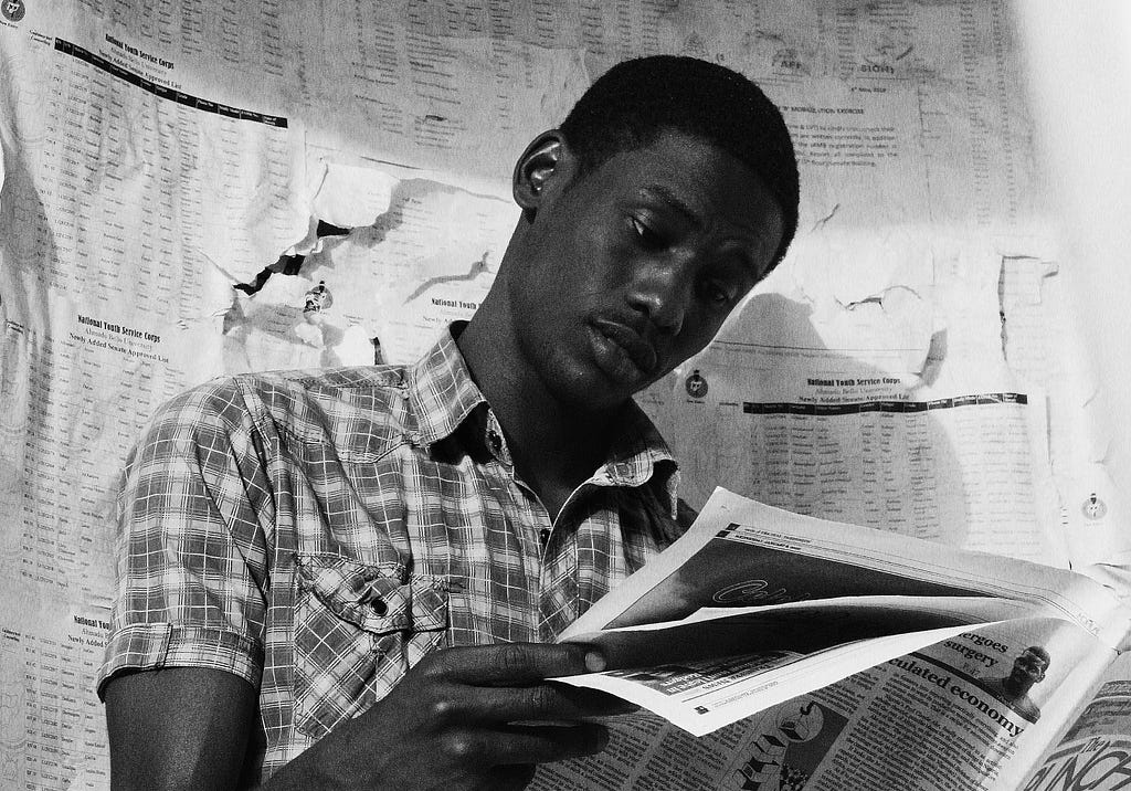 young Black person reading a newspaper