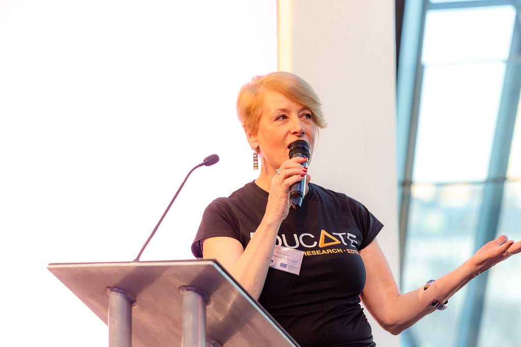 Rose on the podium at EDUCATE’s 2019 Demo Day with a mic in her hand