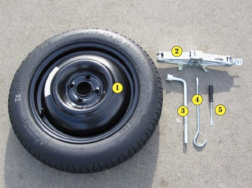 Labeled replacement tire with its tools laying on the ground.