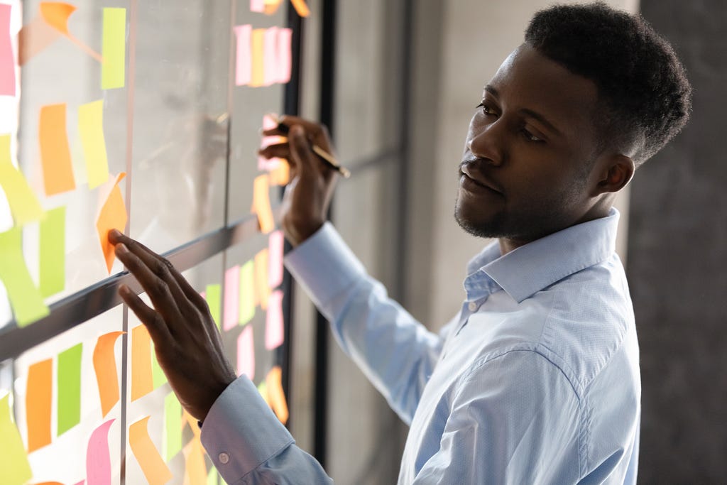 A man writing and organizing post-it notes.