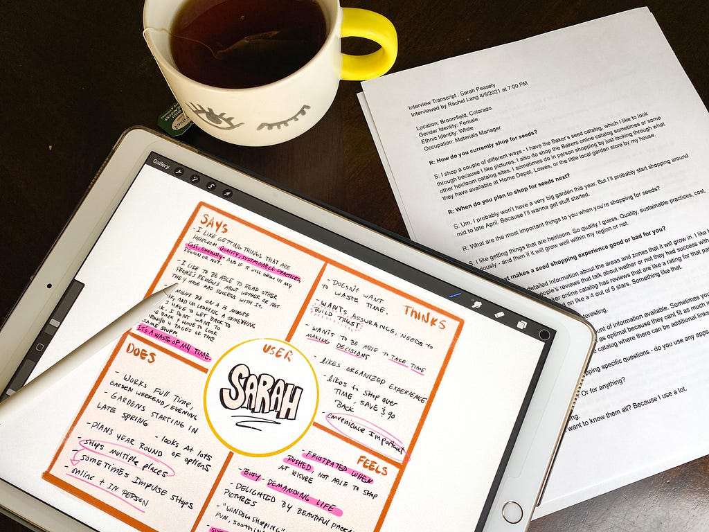 A tabletop with an empathy map on an iPad screen, a printed interview transcript, and a cup of tea.