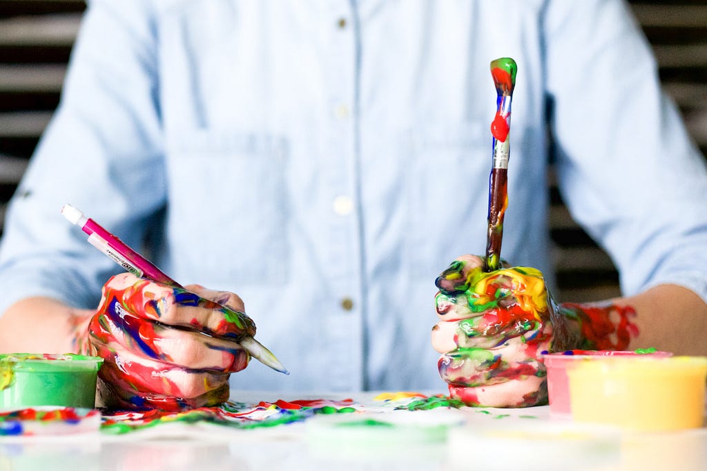 Person with hands full of paint stting at a desk