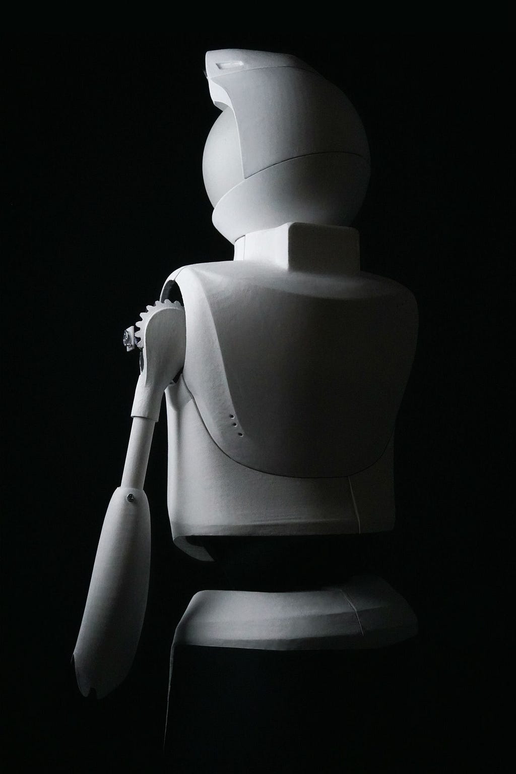 Dramatic black and white photo of Quori robot taken from behind. Shadow falls on robot’s back and looks ominous.