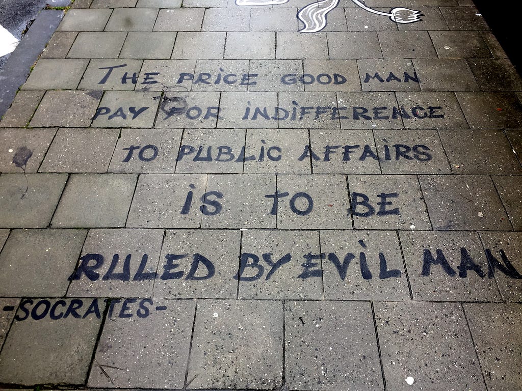 Image of graffiti on pavement outside EU Commission headquarters: “The price good men pay for indifference to public affairs is to be ruled by evil men”