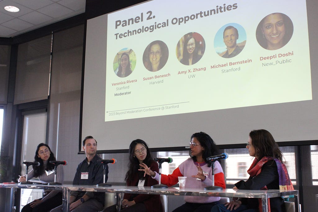 Veronica Rivera, Michael Bernstein, Amy Zhang, Deepti Doshi, and Susan Benesch sitting at a table with a screen over them that reads “Panel 2: technological opportunities”