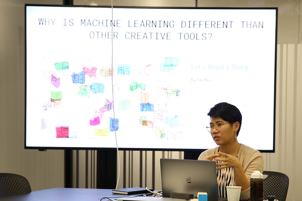 A woman sits in front of a screen giving a presentation about about ml5.js