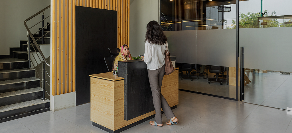 A woman talking to a receptionist at a corporate reception.