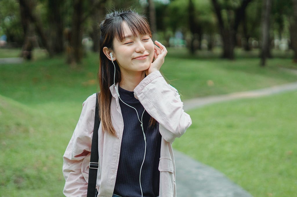Asian woman enjoying music via earbuds
