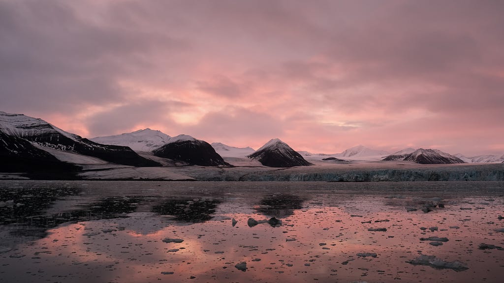 Image of a glacier in Svalbard illuminated  by natural pink and peach sunlight at either early dawn or evening.