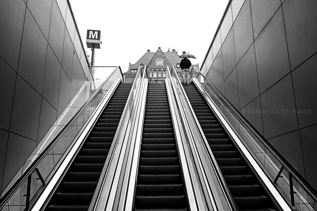 black and white photo looking up the escalator at an Amsterdam metro station