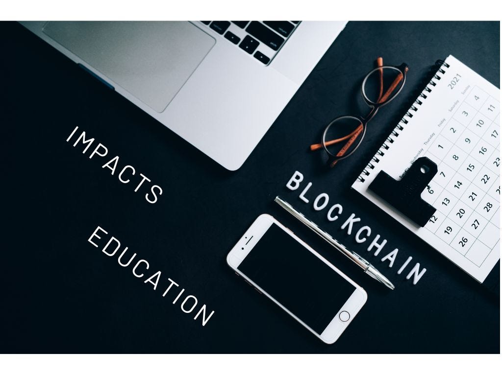 Image of a computer, a note book and a phone on a table with the words : Blockchain, Impacts and Education, in upper case letters written on the table