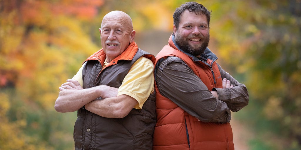 Dr. Jan Pol and Charles Pol stand back to back in vests in a field