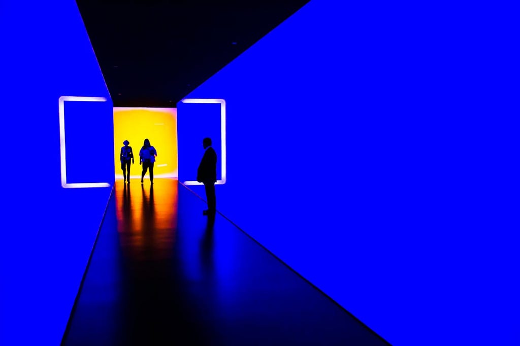 Three people entering a dark blue hallway.