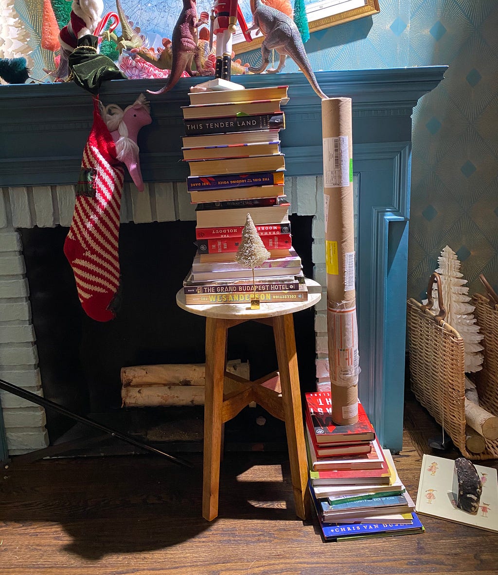 Plastic dinosaurs propped up on a gigantic stack of books.