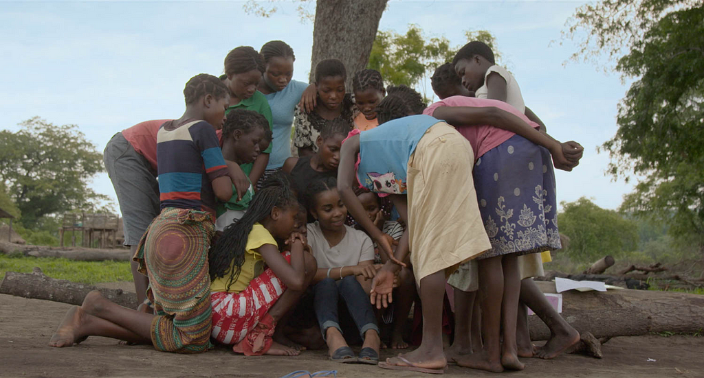 Dominique Gonçalves, a Mozambican elephant ecologist, is surrounded by young Mozambican girls as she talks to them about elephants.