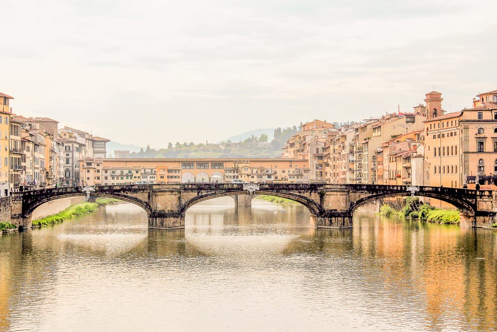 two bridges over river with colourful buildings lining the edge