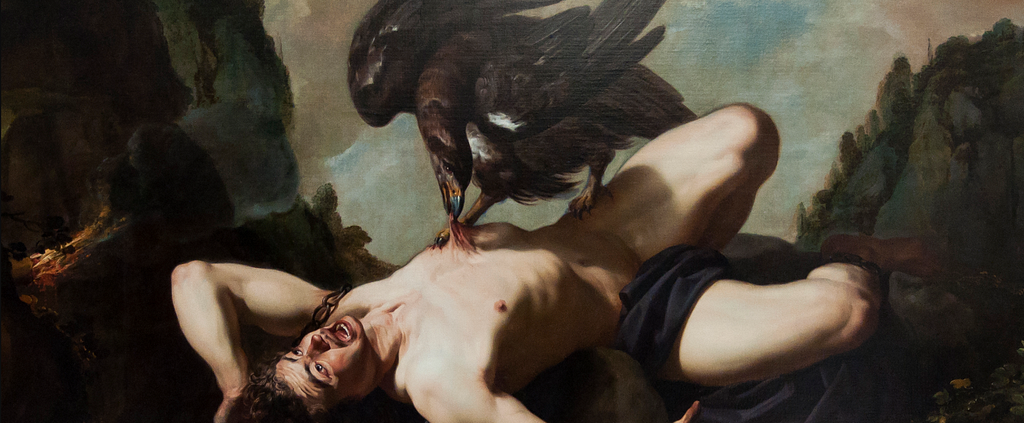 A light-skinned man lies naked, prone on a rock. His arms are bound with chains, and his mouth is open in a yell. A large, black bird stands on top of him, biting at his abdomen with its beak.