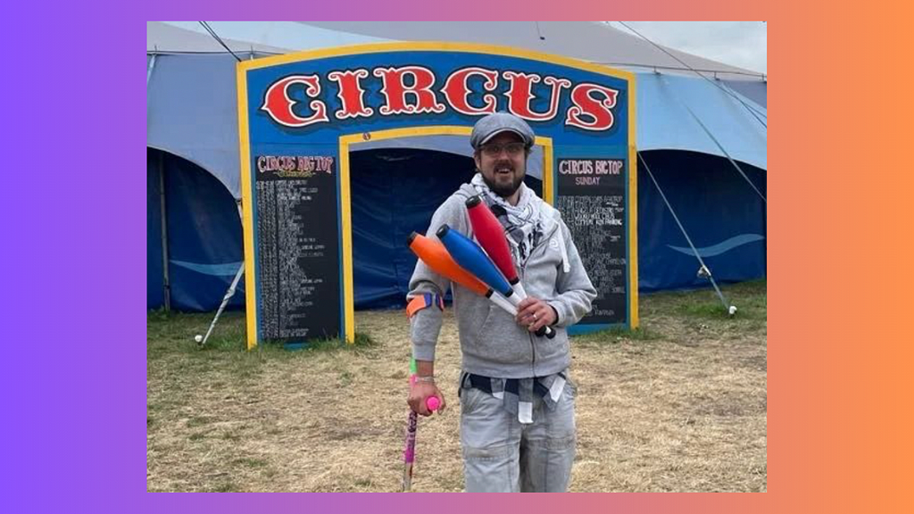Picture of me resting on my crutch, holding juggling clubs, outside of the Circus tent as Glastonbury Festival