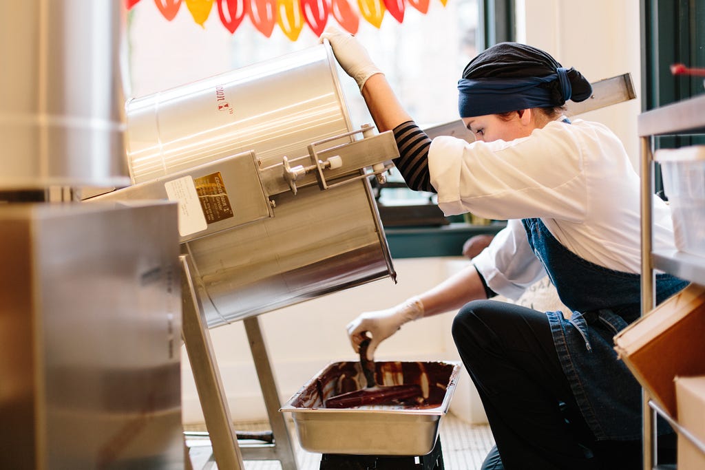 Merri Schwartz cleans chocolate from a pan.