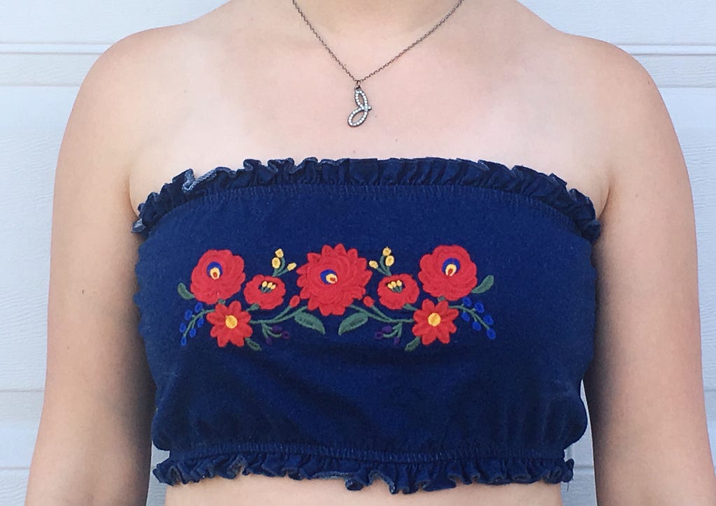 A blue tube top with red flowers embroidered onto it.