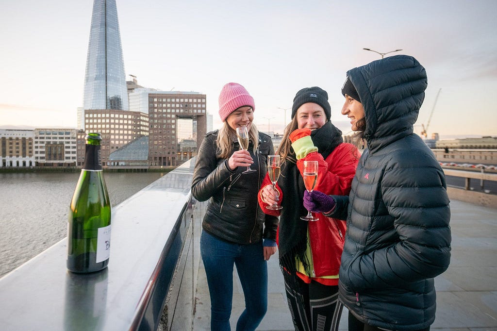 Friends enjoy a glass of Prosecco while watching the sunrise on London Bridge.