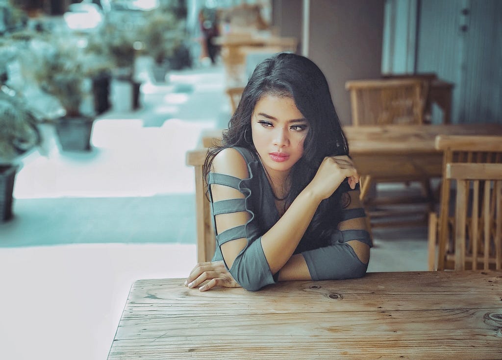 A woman sits alone with a sad expression on her face.