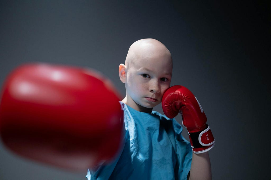 A child wearing a blue medical gown punching with red gloves.