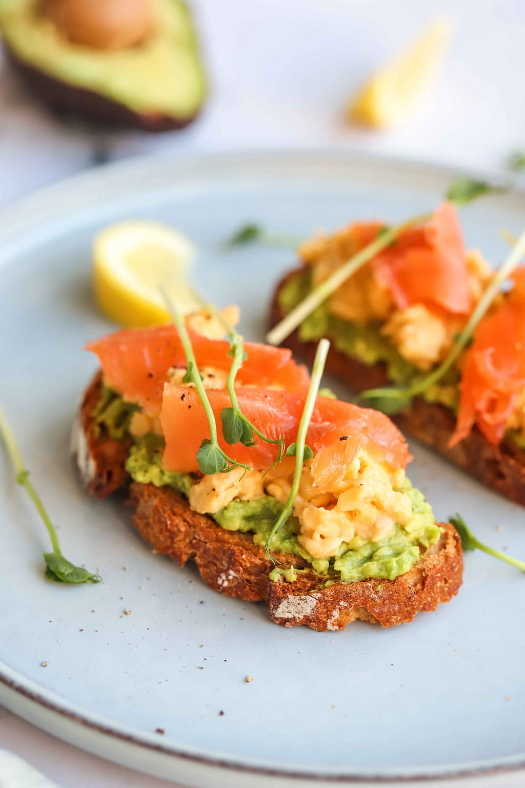Avocado toast with scrambled eggs and smoked salmon, garnished with bean sprouts. Photo by FIT & NU.