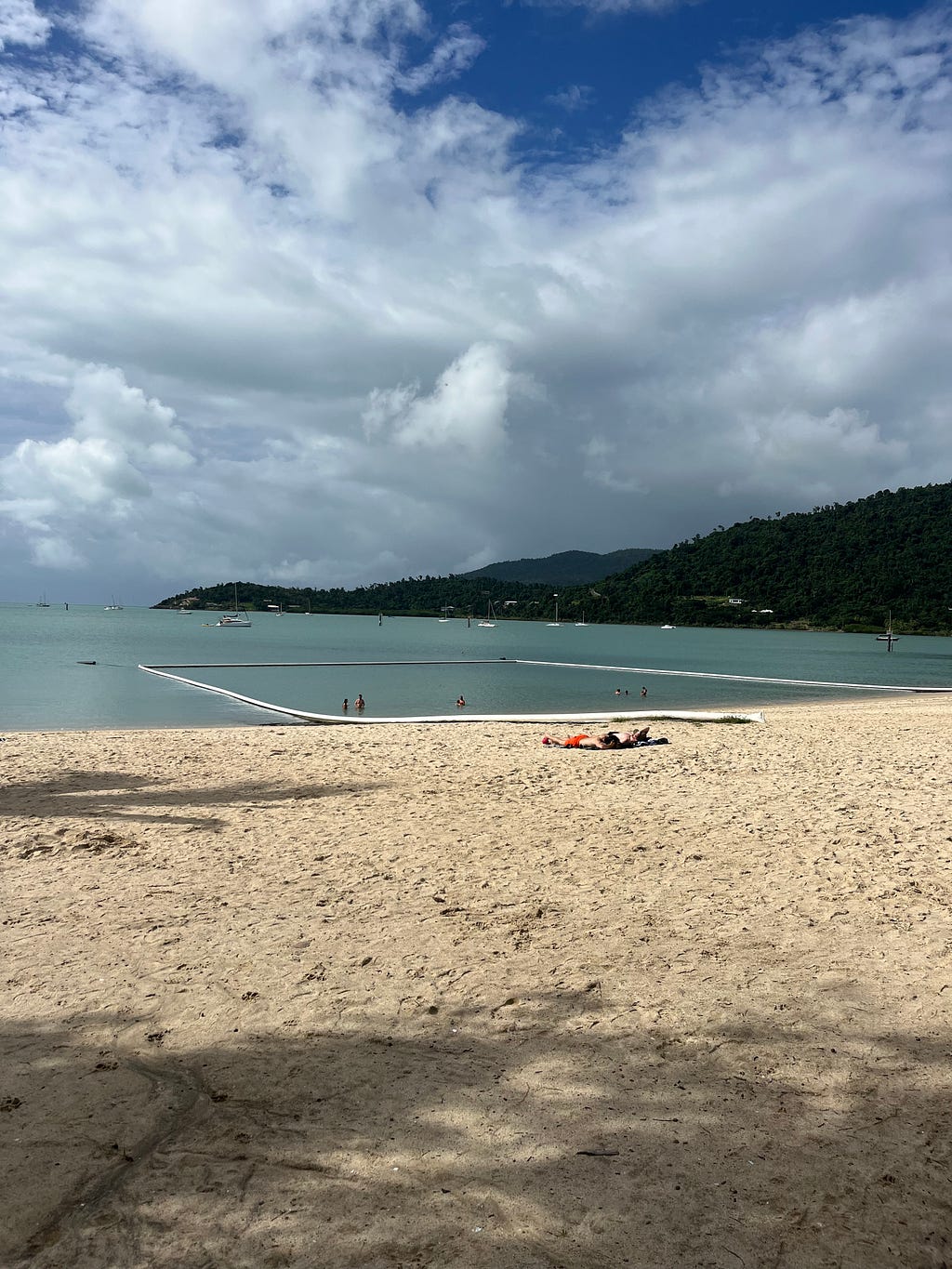 Airlie Beach Bay and Beach — Pristine turquoise waters and sandy shoreline surrounded by lush greenery, ideal for a tropical vacation in Queensland, Australia.