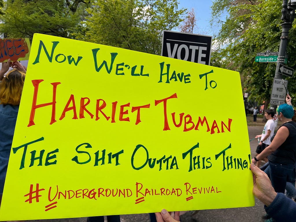 Sign reading “Now We’ll Have To Harriet Tubman The Shit Outta This Thing! #Underground Railroad Revival (each first letter after the hashtag is underlined.