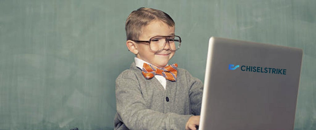 Boy with large glasses and bowtie typing on a laptop
