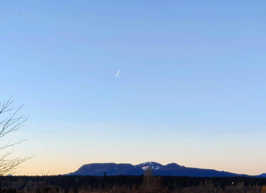 A meteor or a possible space re-entry in the evening sky over the mountains.