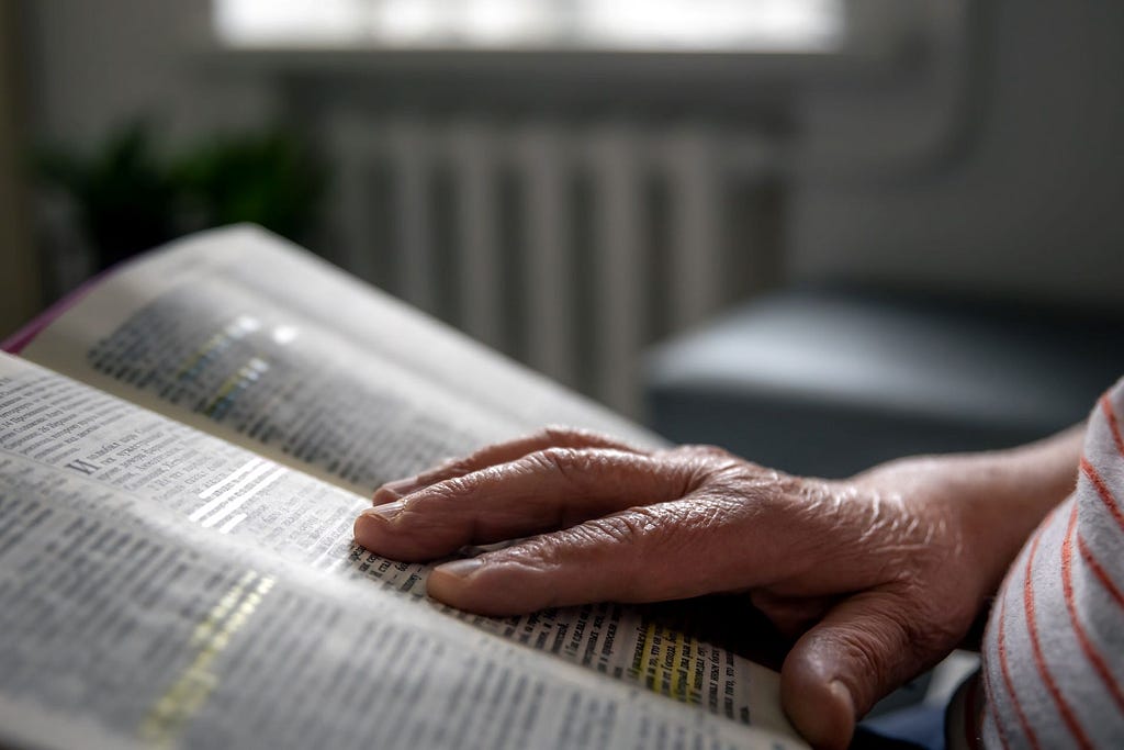 A photo of an old woman reading the Bible