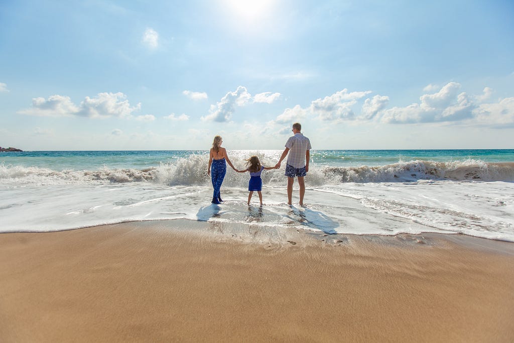 a family of three on the beach to represent the contribution of a dad to making a happy family