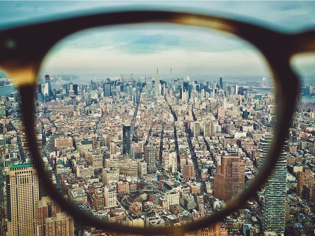 A city landscape is seen through the lens of an eyeglass