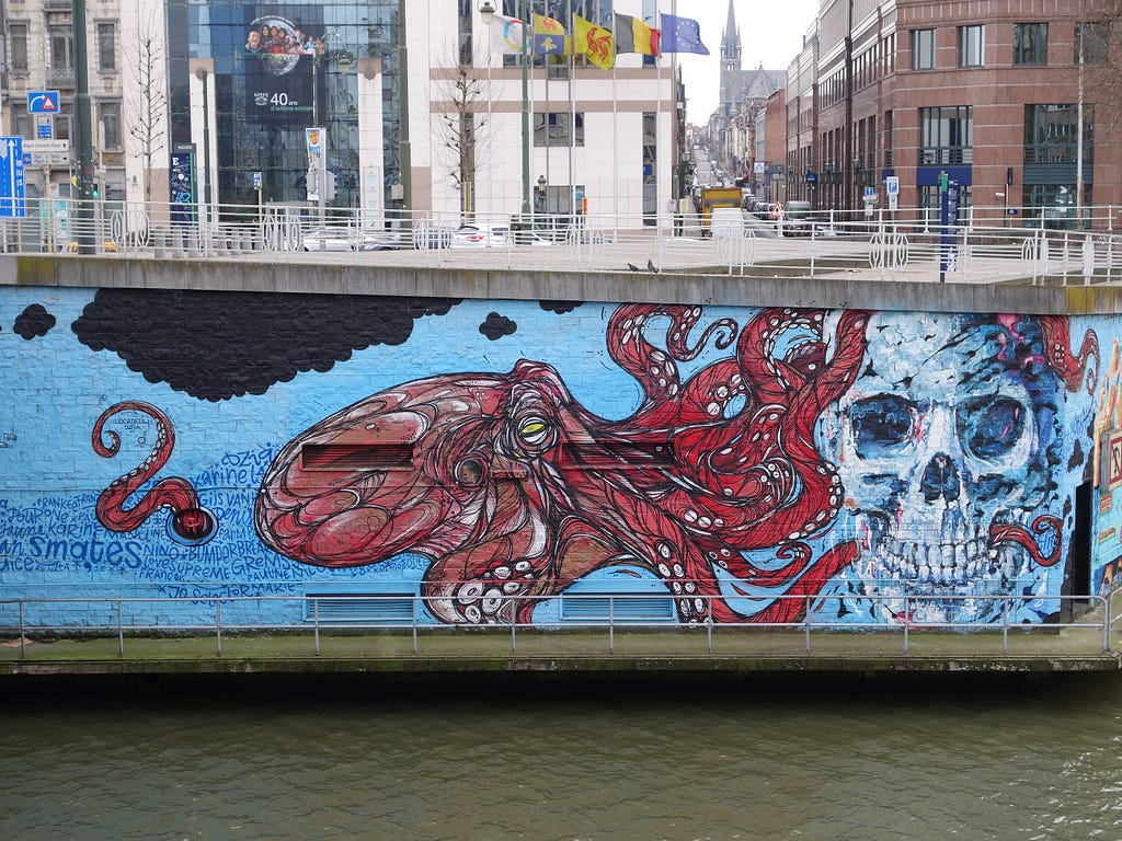 The wall overlooking a canal has a painting of a red octopus and a skull.