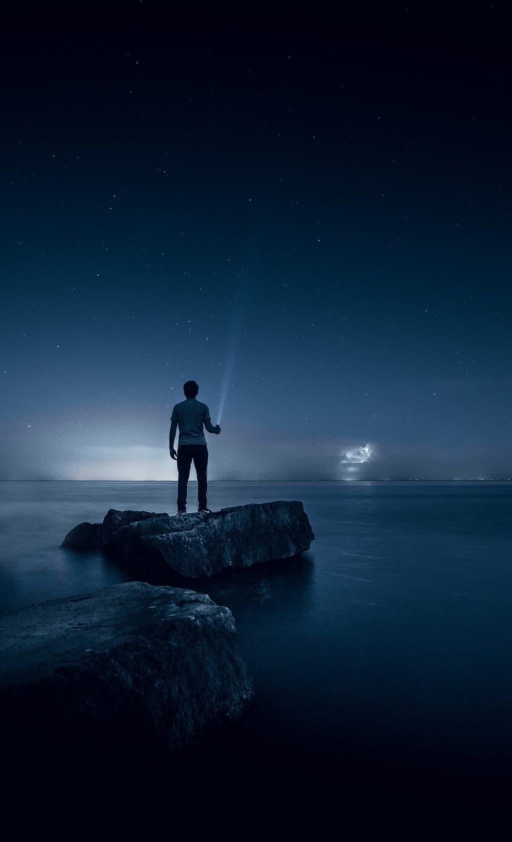 Man holding a torch looking at night sea