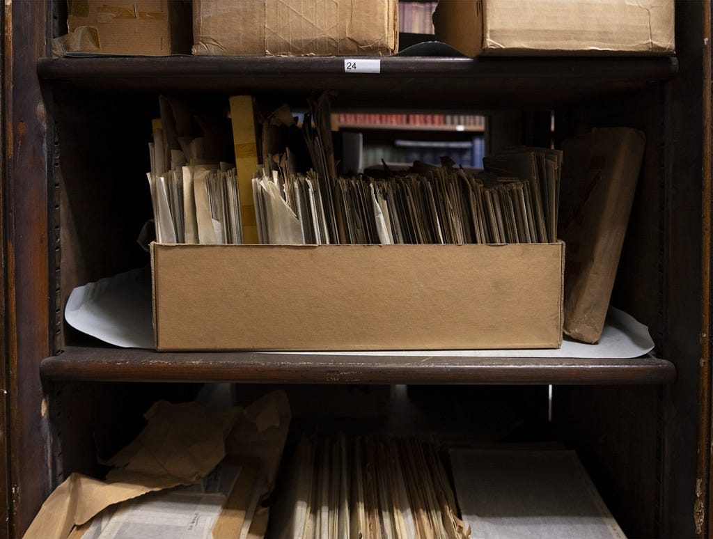 A cardboard box of glass negatives on a shelf in the library basement