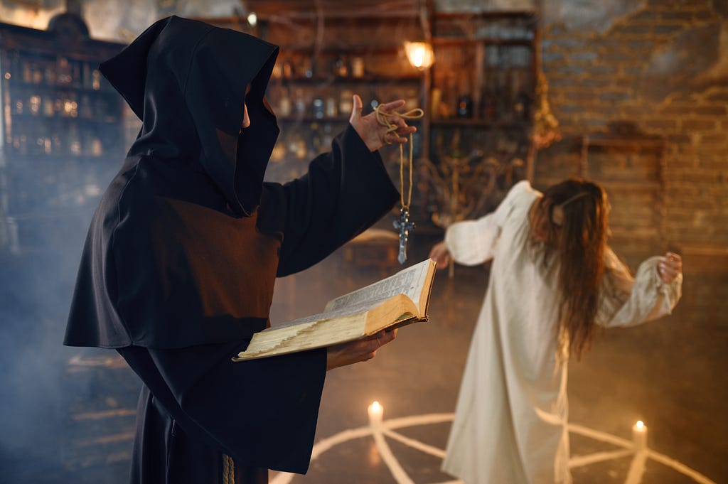 Image of a hooded figure performing an exorcism in a dimly lit, smoky room. The figure holds an open book in one hand and a crucifix in the other, with a possessed person in a white gown contorting in the background within a circle of candles.