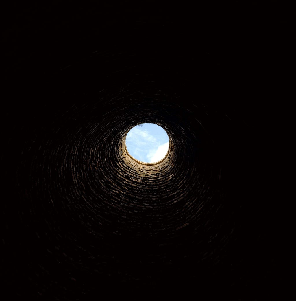 A circle of sky viewed through the brick chimney of a kiln.