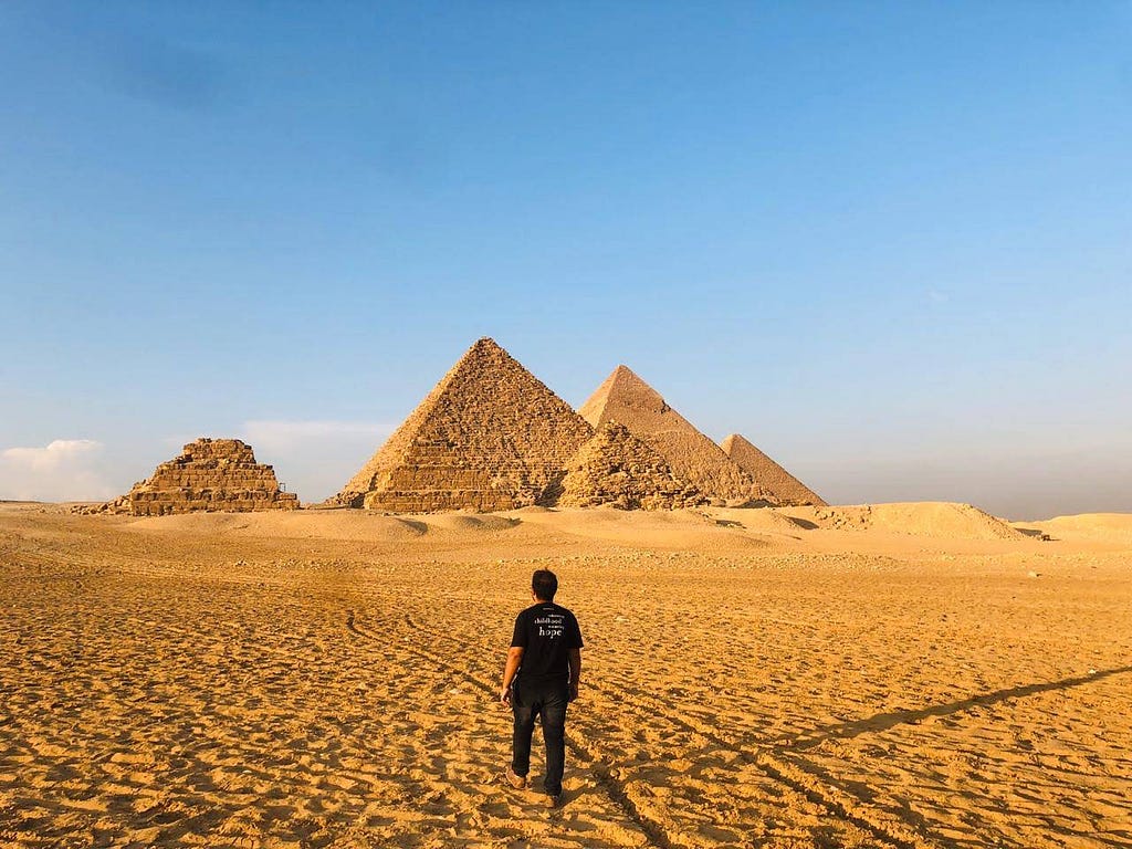 The Great Pyramids of Giza with author walking in the sand