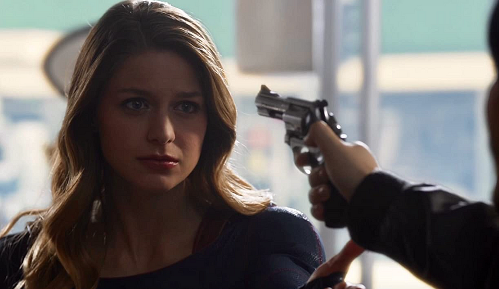 Melissa Benoist as Supergirl with a gun pointed in her face.