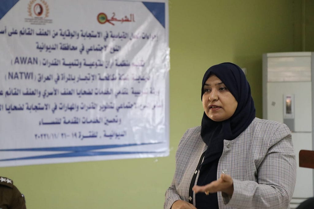Photo of Feryal Alkaabi, Director of Awan Organization. She is standing, speaking in front of a white board, wearing a headscarf.