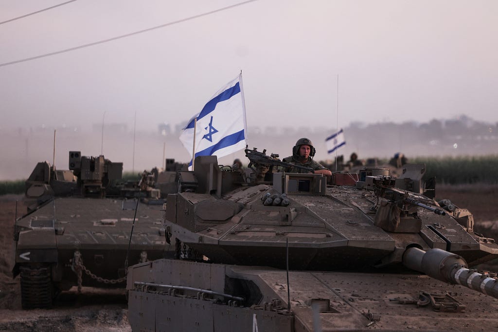 An Israeli soldier looks out from a tank as an artillery unit gathers near Israel’s border with the Gaza Strip, in southern Israel, October 12, 2023. Photo by Ronen Zvulun/Reuters