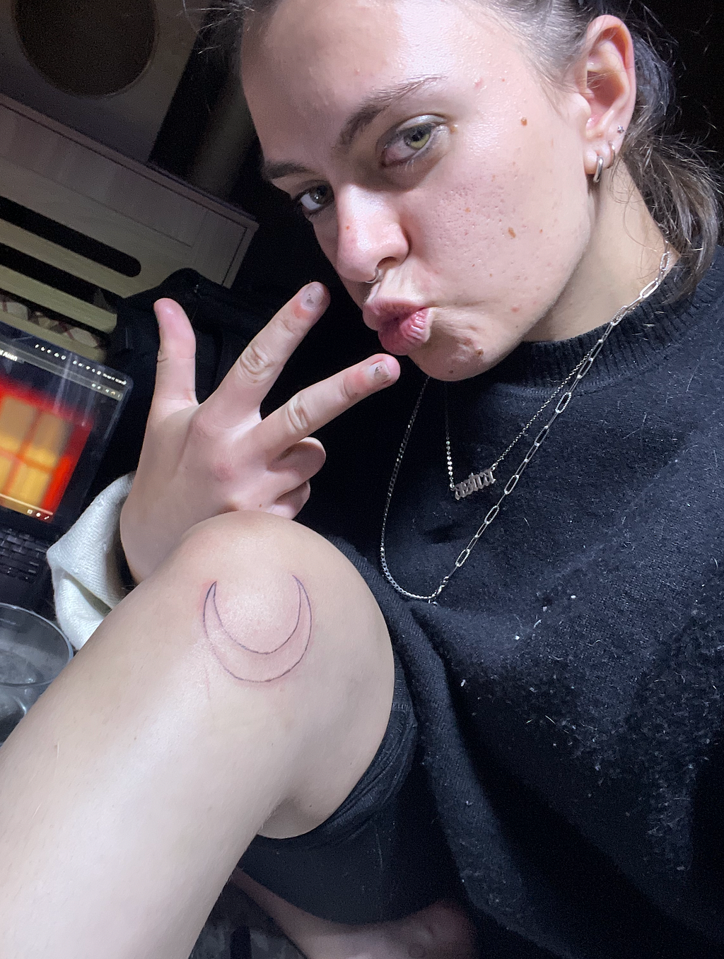 Me with my new stick and poke tattoo, which is a cresent moon that wraps around the bottom of my knee. I’m throwing up a peace sign and doing a duck face.