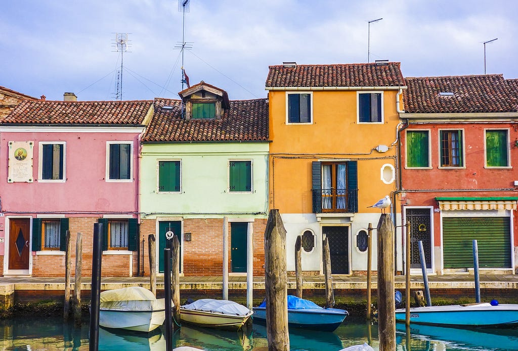 brightly colored houses on water with small boats in front