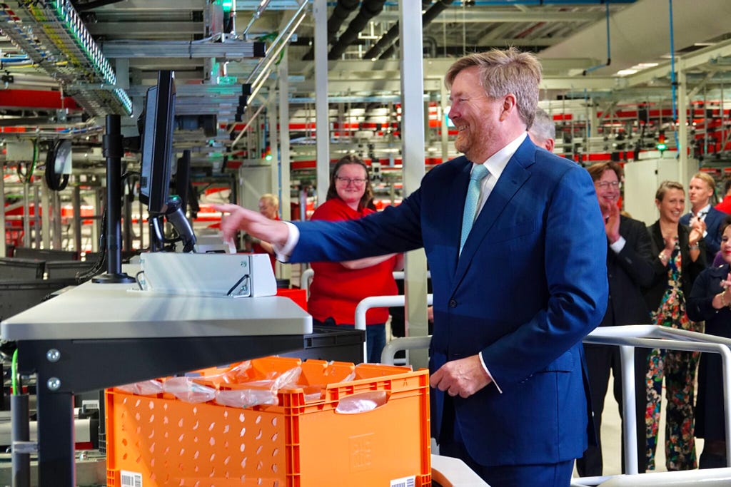 A photo of King Willem-Alexander of the Netherlands touching an interface at one of the automated warehouse workstations